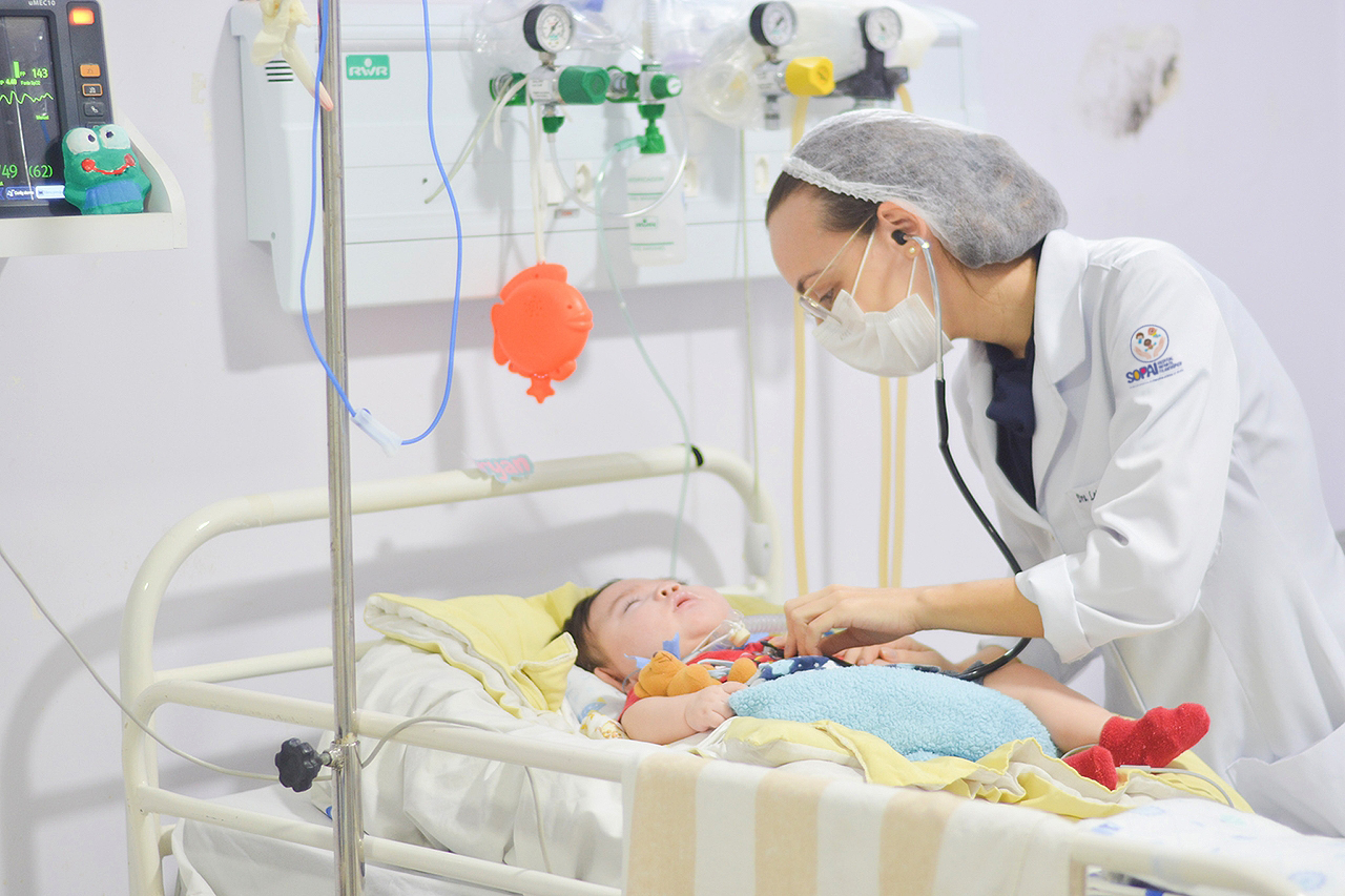 Médica pediatra auscultando um bebê internado em leito do Hospital SOPAI